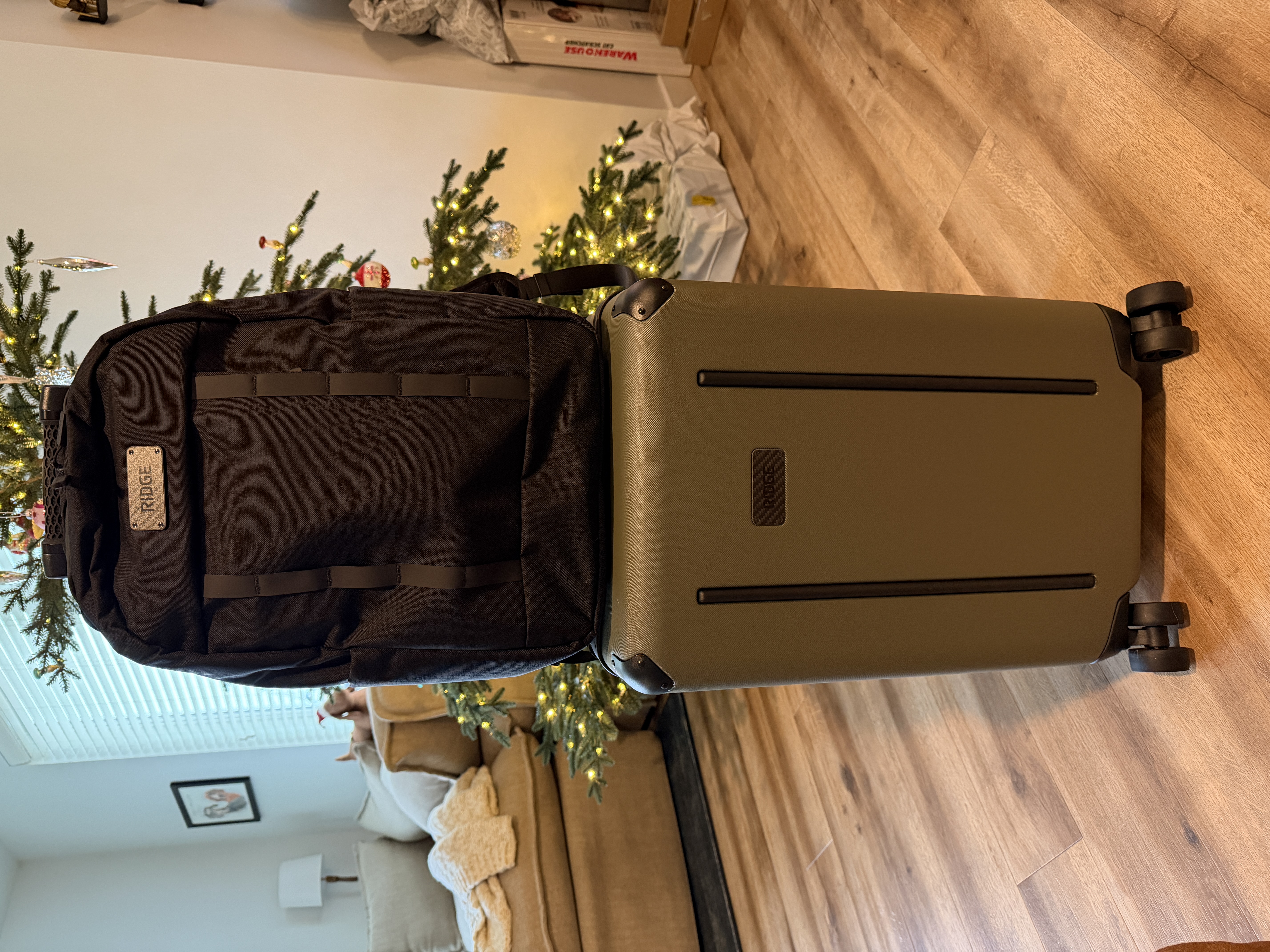 A black backpack sitting on top of an olive green carry-on suitcase.