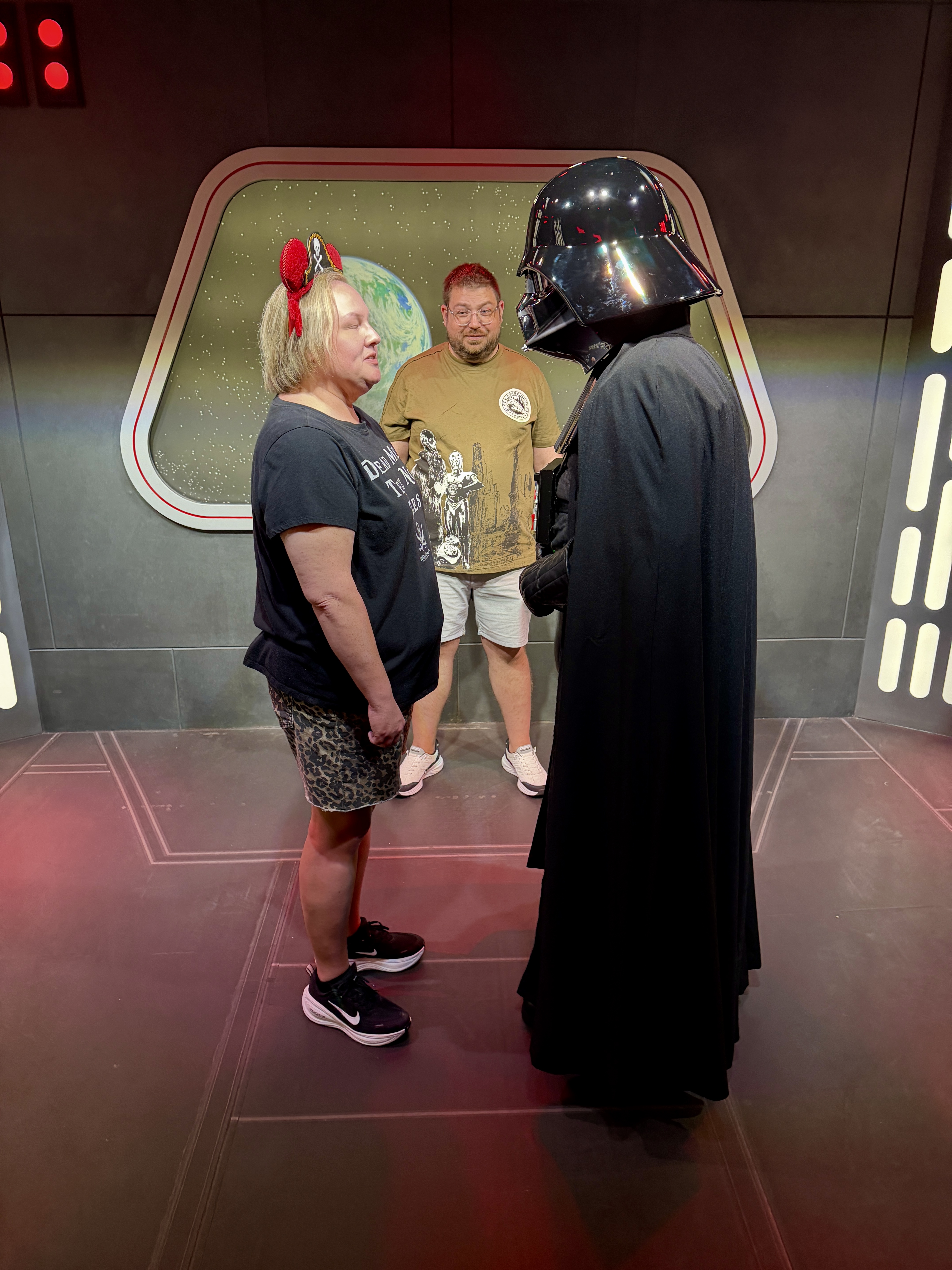 Darth Vader leaning in to talk to a guest on a Star Wars set.