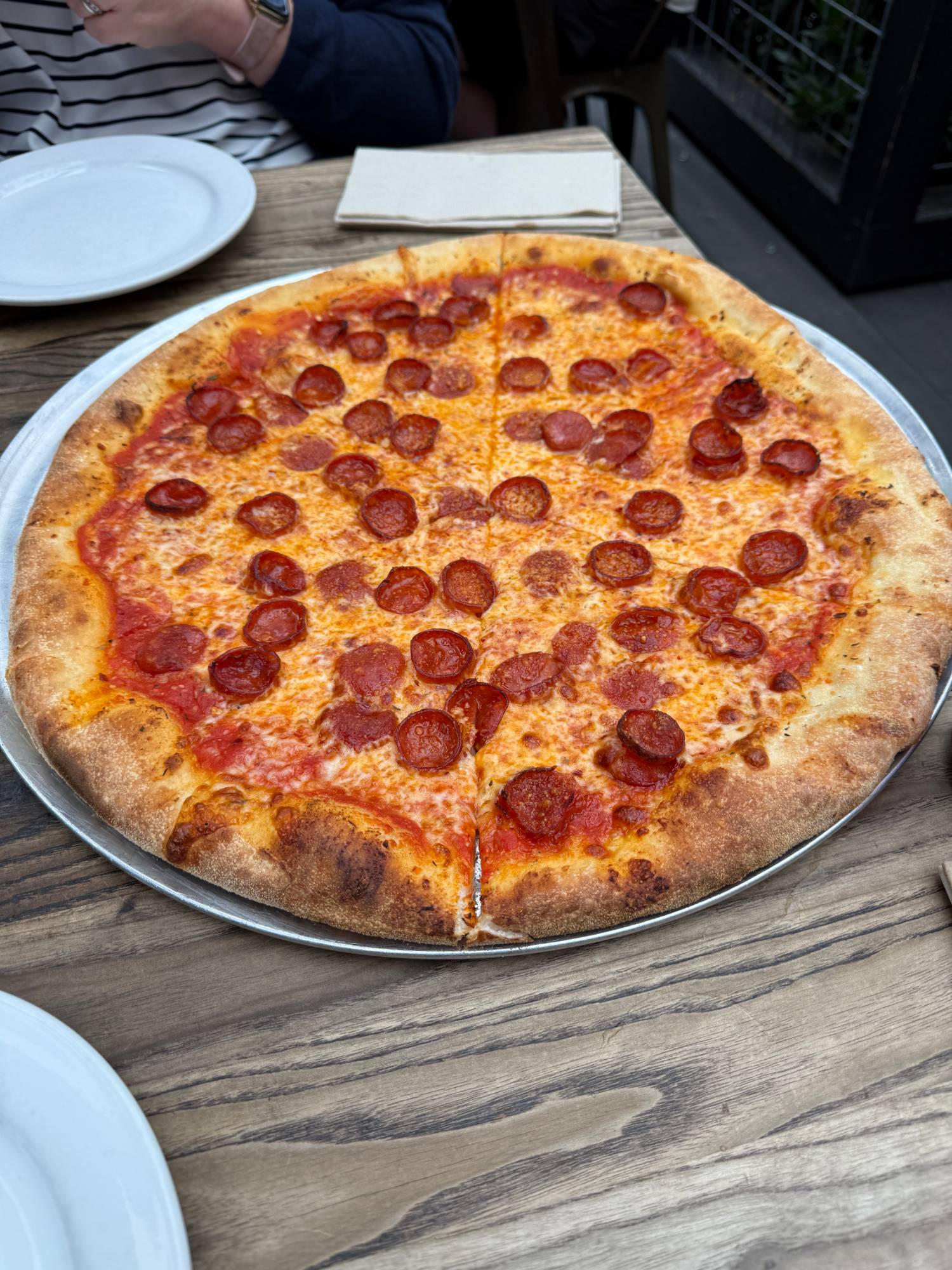 A whole New York-style pepperoni pizza on a metal tray at Spark.